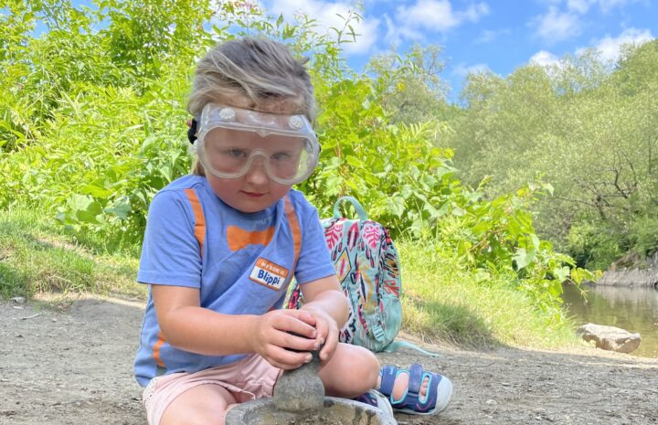 child with safety goggles plays with mortar and pestle