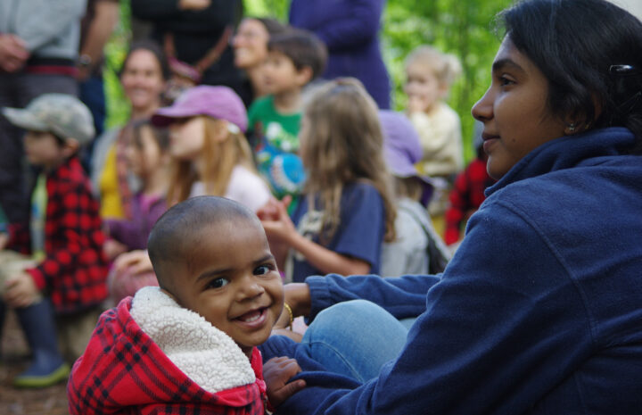 families with young children gathering, with one child looking at camera and smiling